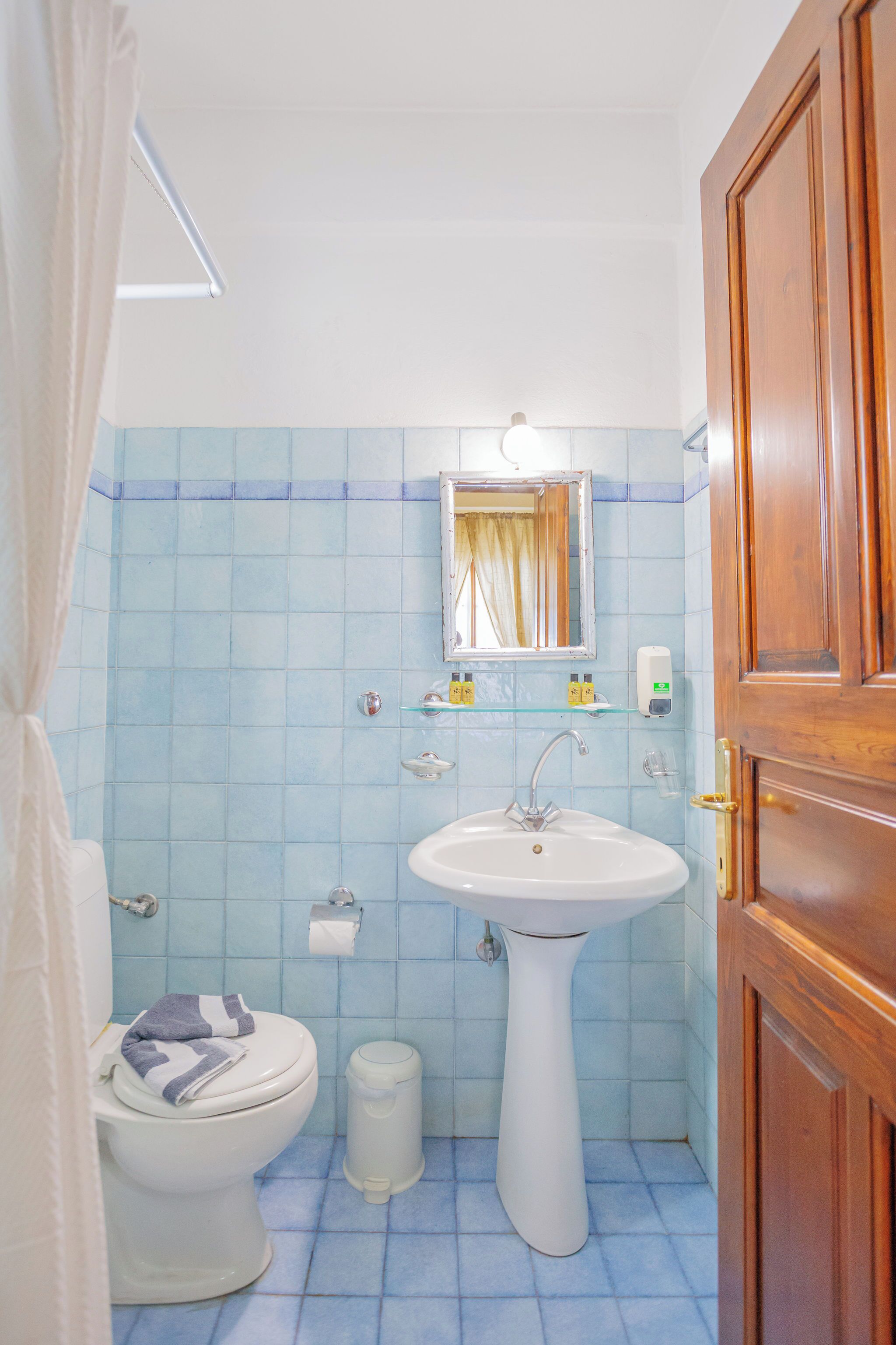 A bathroom with a toilet, sink, and mirror.