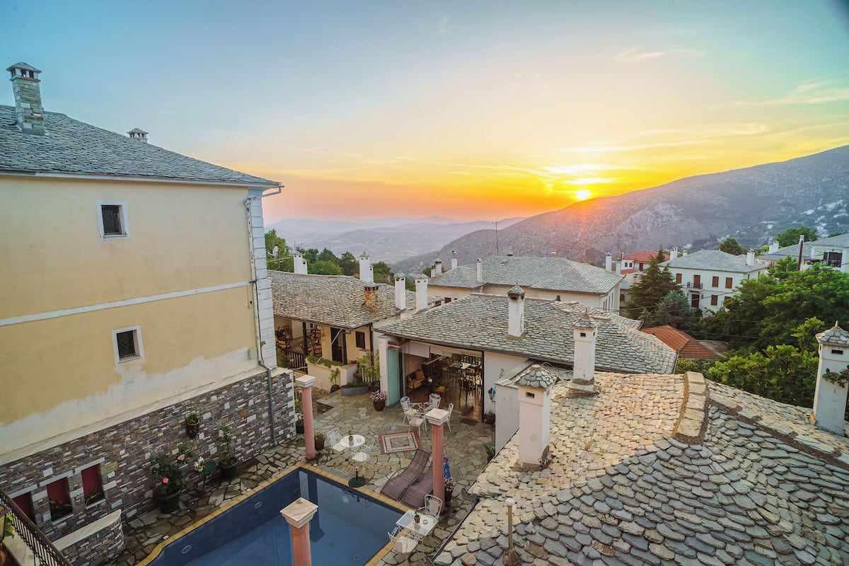 A courtyard with a pool, stone walls, and traditional architecture.