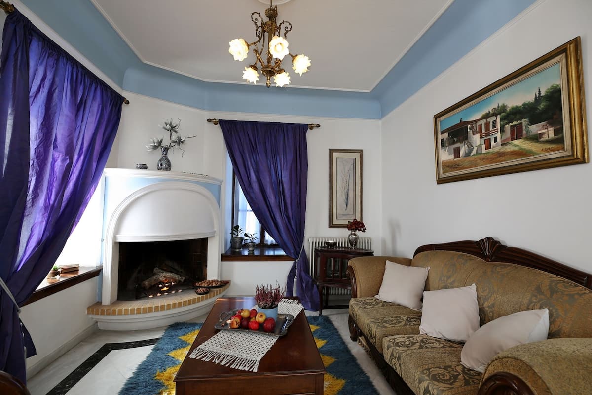 A living room with a fireplace, a sofa, a coffee table with fruit, and a painting on the wall.