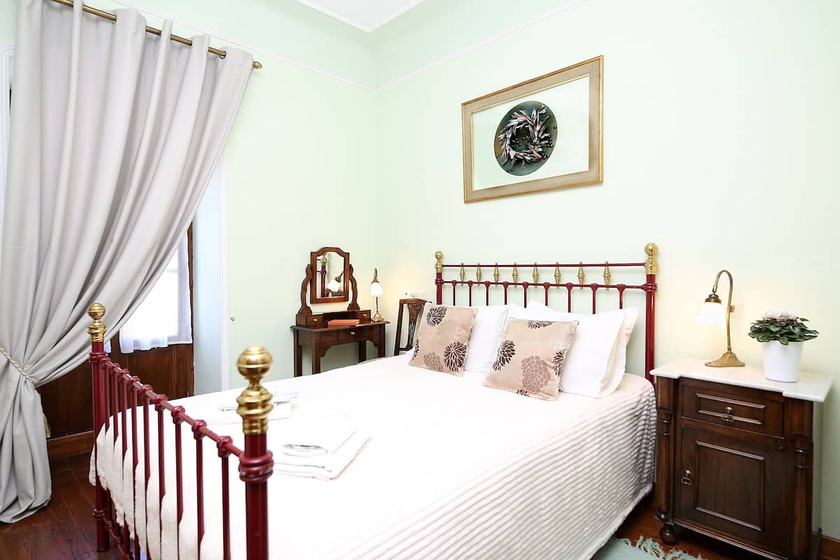 A neatly made bed with a headboard, a bedside table with a lamp, and a framed picture on the wall.