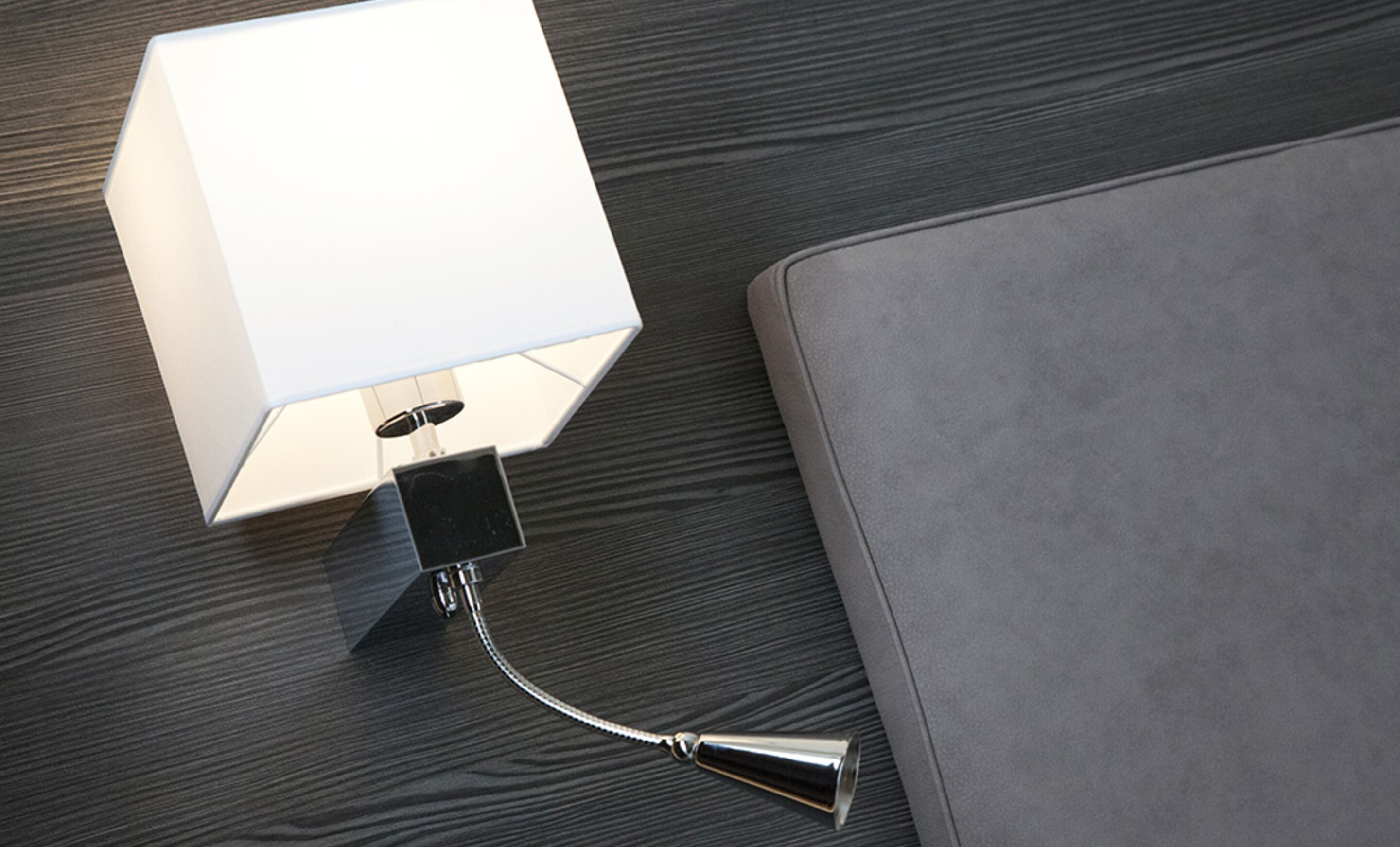 A modern lamp with a metallic base and a flexible neck on a wooden floor.