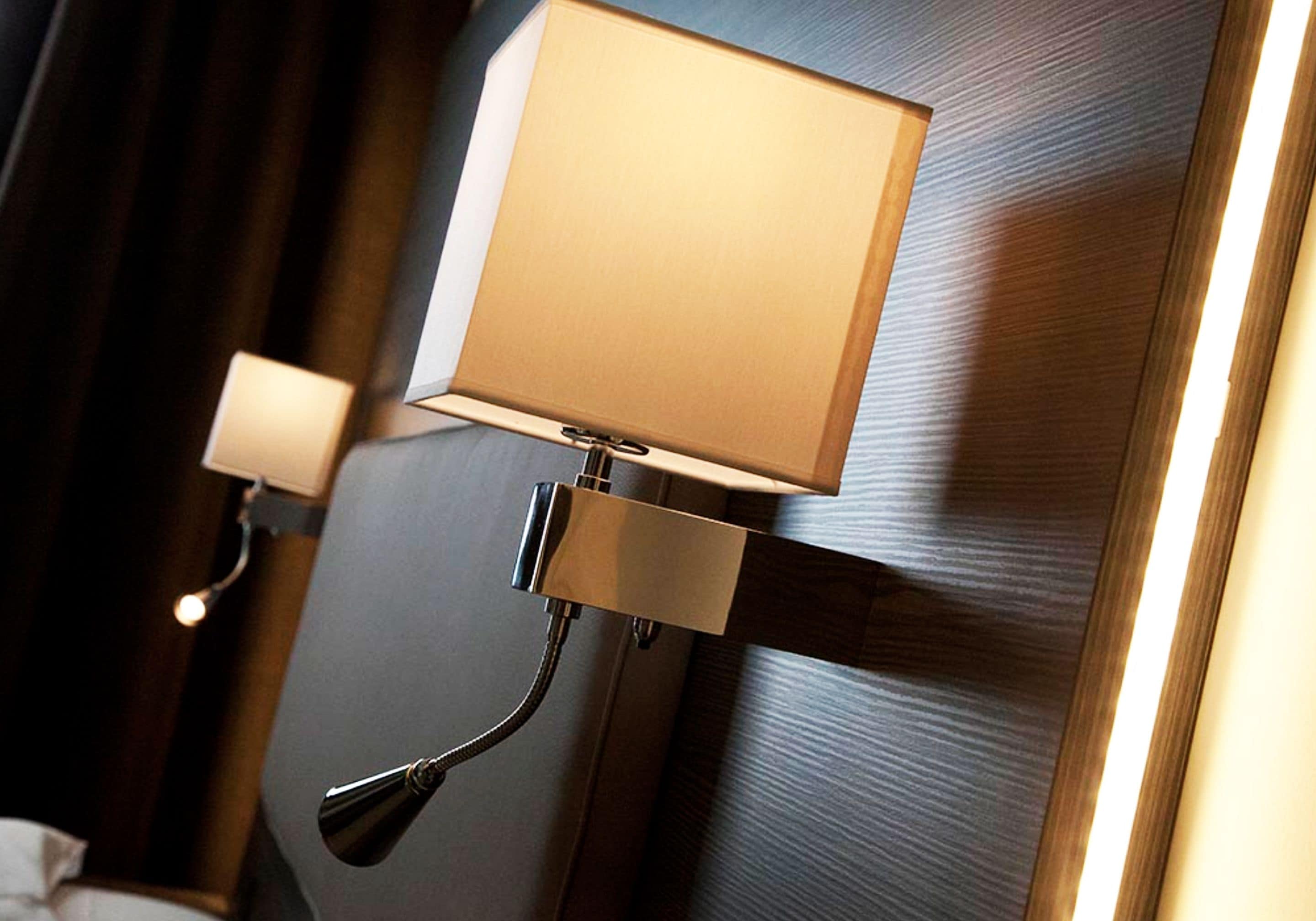 A wall-mounted lamp with a rectangular shade and a flexible arm.