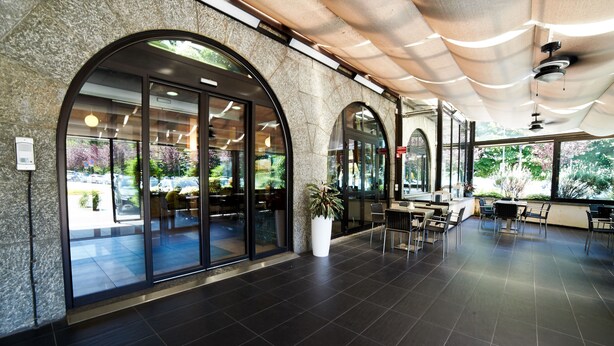 A spacious indoor area with large windows, a seating area, and a potted plant.