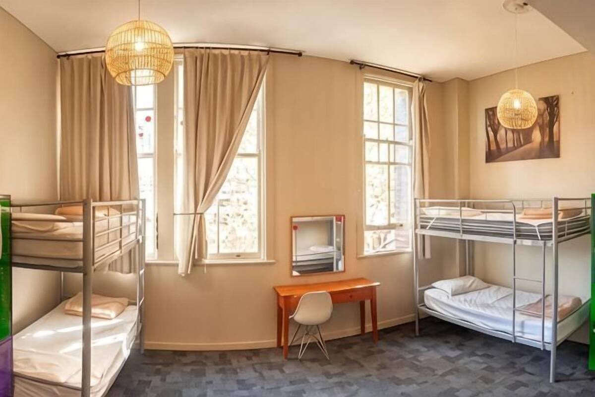 Una habitación con literas, un escritorio, una silla y un televisor.