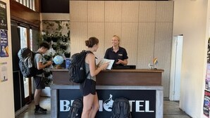 A reception desk with a sign reading "B&B TEL" and two people interacting near it.