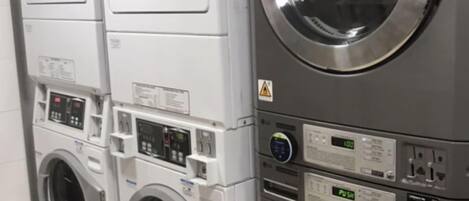 A row of stacked front-loading washing machines in a commercial setting.