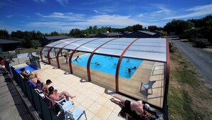 Una piscina techada con gente sentada y nadando.