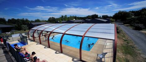 Ein überdachter Pool mit badenden und entspannten Personen.