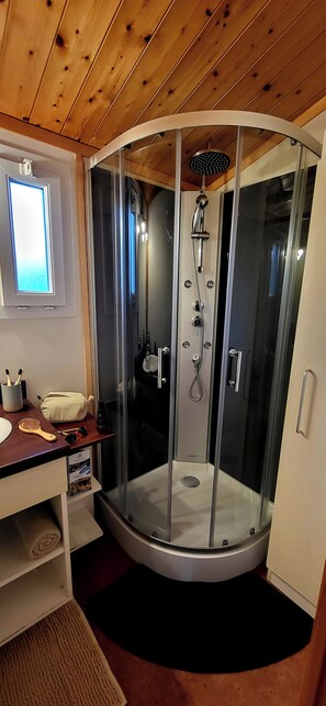 A modern bathroom with a glass-enclosed shower, wooden ceiling, and a small window. - Terres de France - Hameaux des Marines (Saint-Denis-d'Oleron)