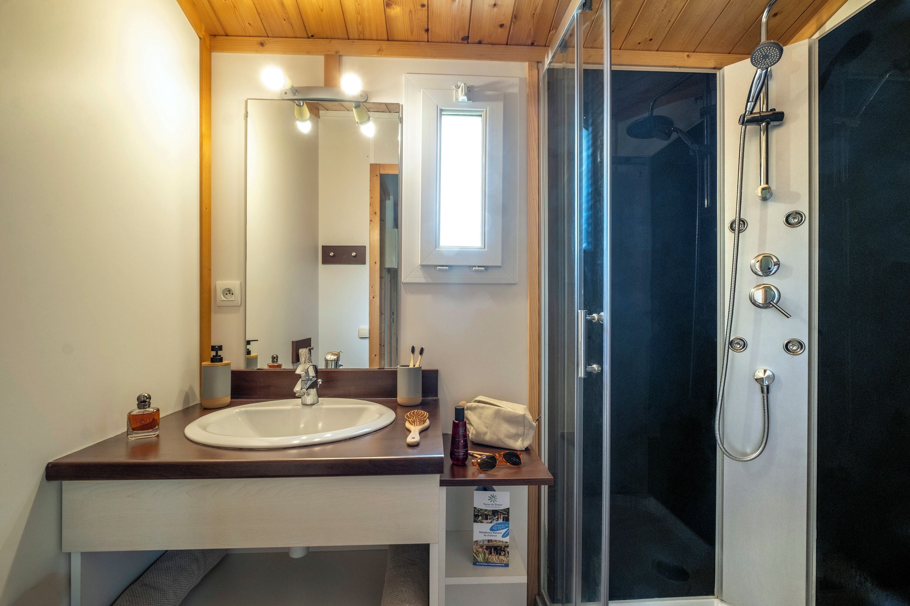 A modern bathroom with a large mirror, a sink, and a shower enclosure.