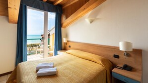 Une chambre d’hôtel avec un lit, une table de chevet, une lampe et une vue sur la plage.
