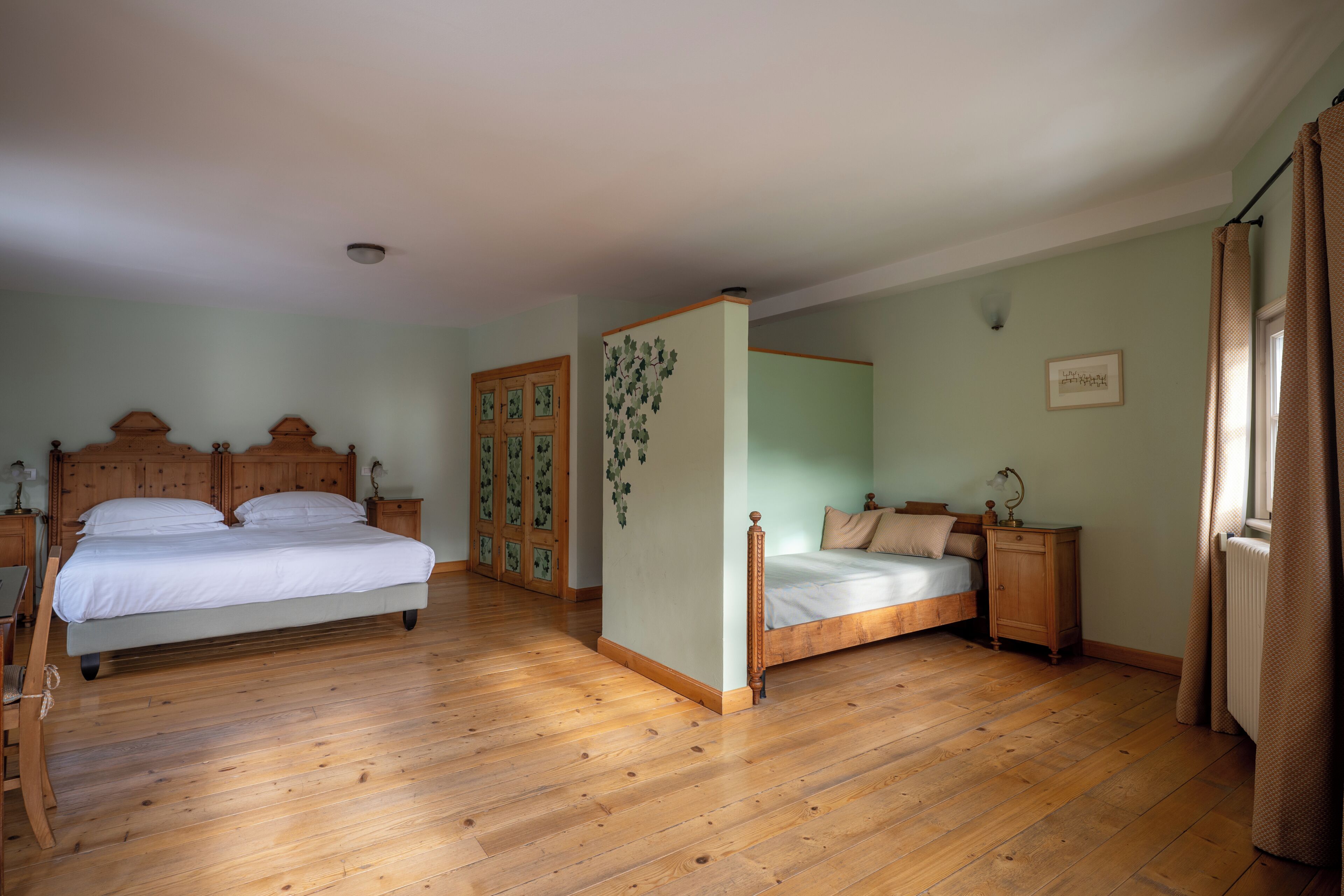 Una camera da letto con due letti, pavimento in legno e arredamento tradizionale.