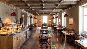 Un restaurant doté de planchers en bois, de hauts plafonds avec des poutres apparentes et d’un long comptoir où sont servis des plats et des boissons.