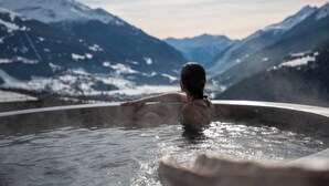 Une personne dans un bain à remous, avec un paysage montagneux en arrière-plan.