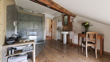 Un baño con ducha, lavamanos y tocador de madera.