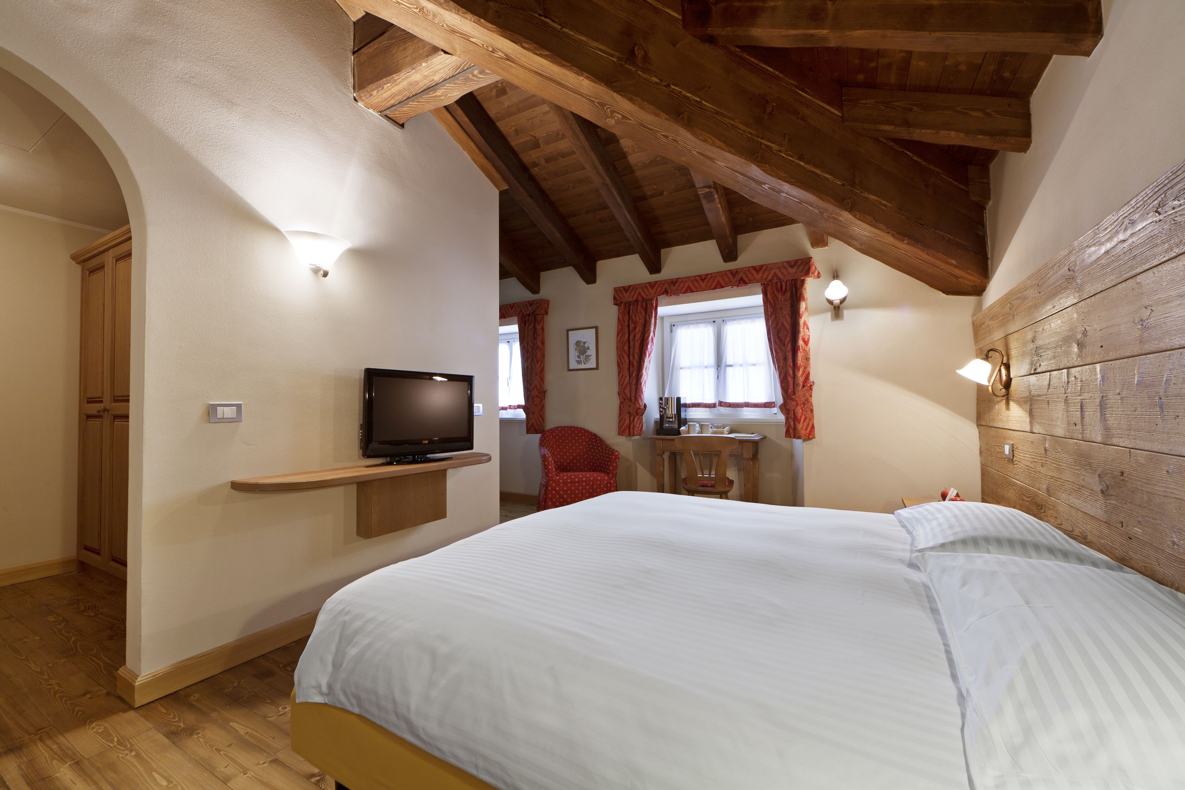 Un dormitorio con una cama, televisor, una silla y una mesita.
