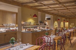 Een restaurant met houten inrichting, een centraal eiland vol gerechten en rode hanglampen.