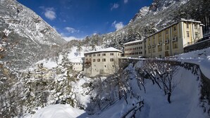 Un paysage de montagne enneigé, avec un bâtiment doté de nombreuses fenêtres et de balcons, entouré d’arbres et de neige.