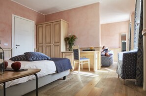 Une chambre à coucher comprenant un lit, une table de chevet et un coin bureau avec une chaise.