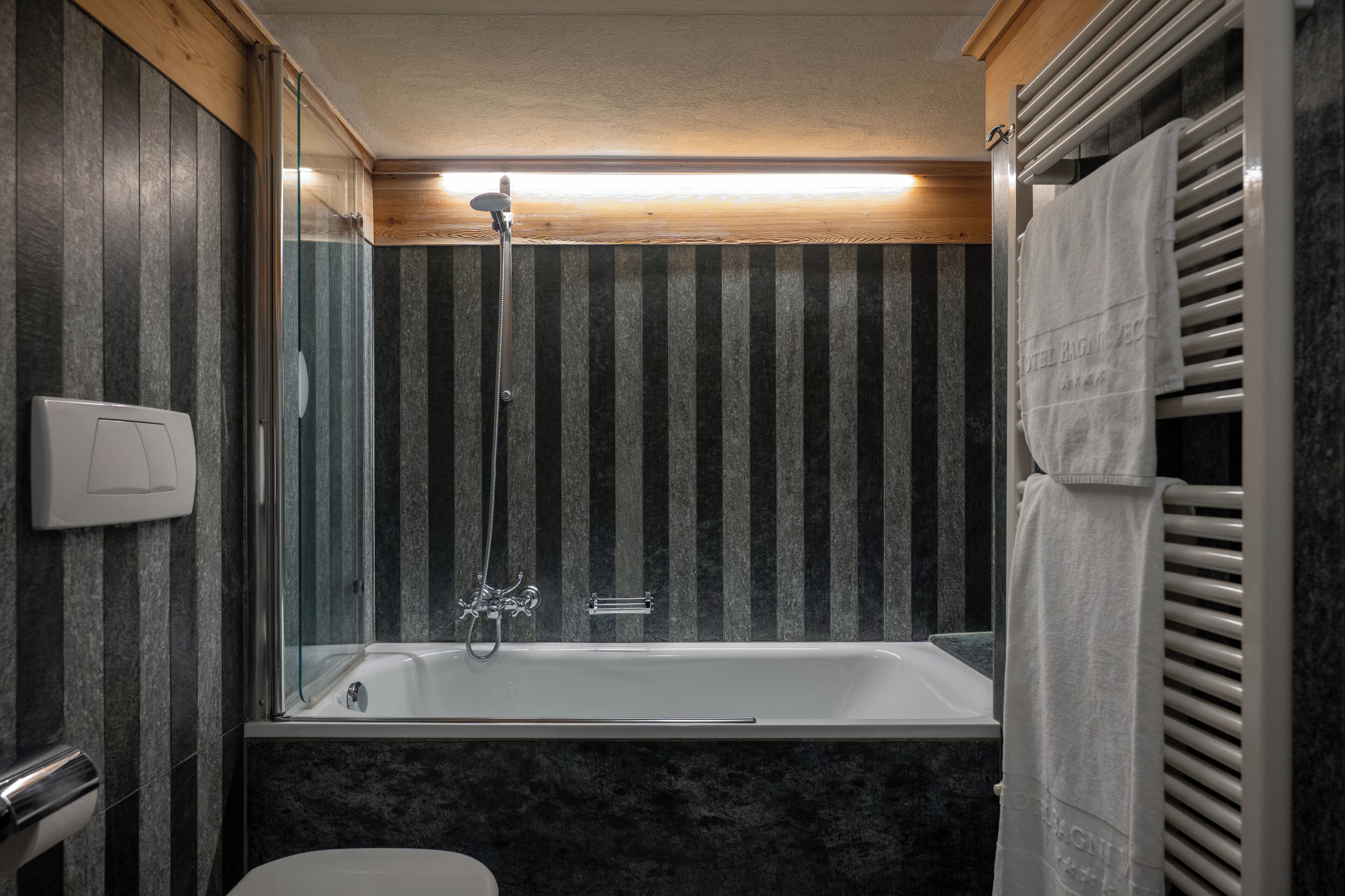 Een badkamer met een bad, een douche en een handdoekrek.