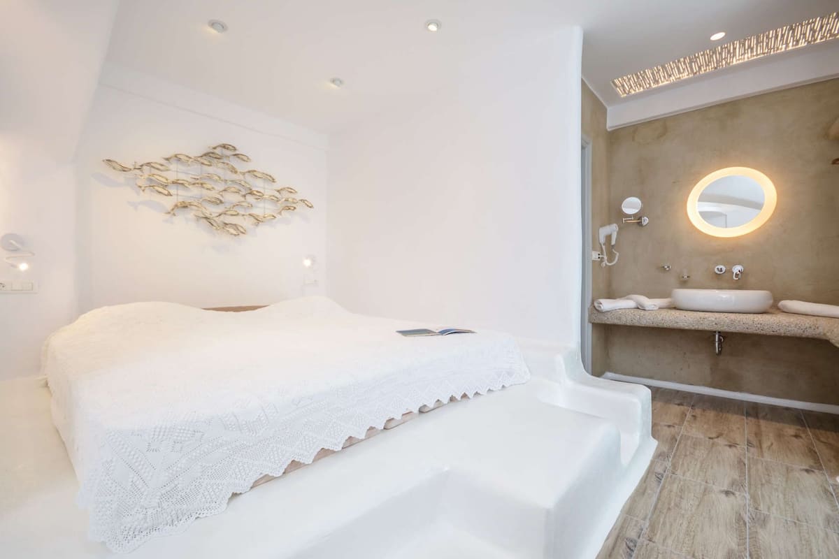 A modern bedroom with a large bed, a bedside table, and a wall-mounted light fixture.