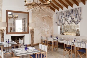 A restaurant with wooden tables and chairs, a fireplace, and a large mirror.