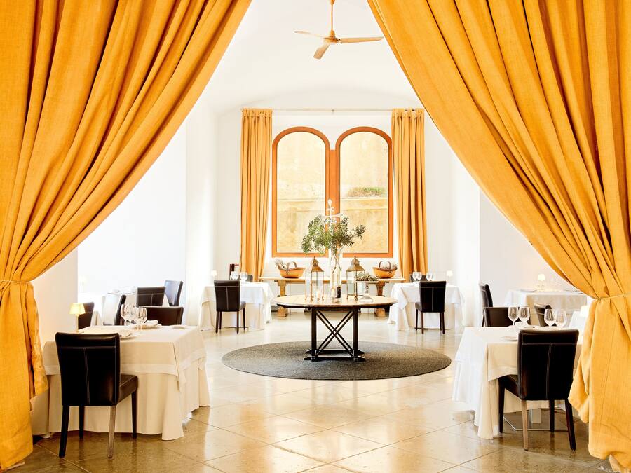 Comedor con mesas redondas, sillas y una pieza decorativa central.