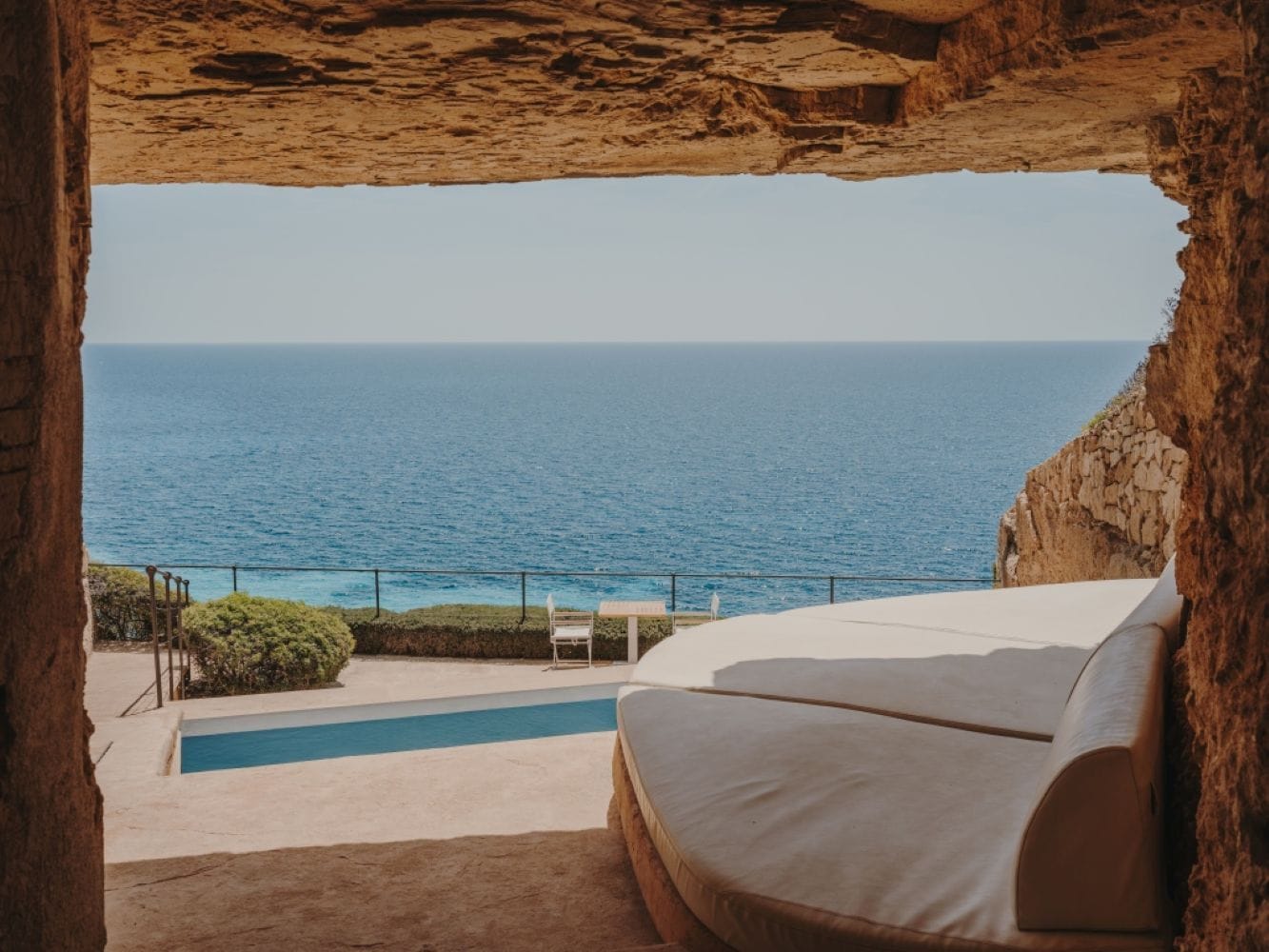 Una habitación con vista al mar, una piscina y un sofá blanco.