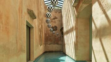 Una piscina interior estrecha con bolas a cuadros colgando del techo, rodeada de paredes con textura.