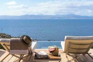 Dos sillones de relax mirando un cuerpo de agua con un horizonte de edificios y monta ñas a lo lejos.