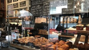 Mostrador de panadería con diversos productos horneados y un menú en pizarra que incluye pollo a la parrilla y hamburguesas.