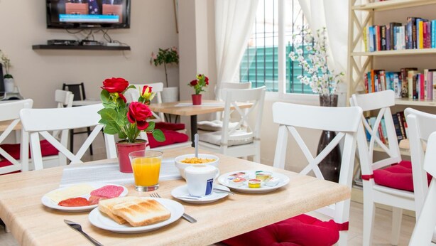 Un espacio para el desayuno con una mesa, sillas, un televisor y una estantería.