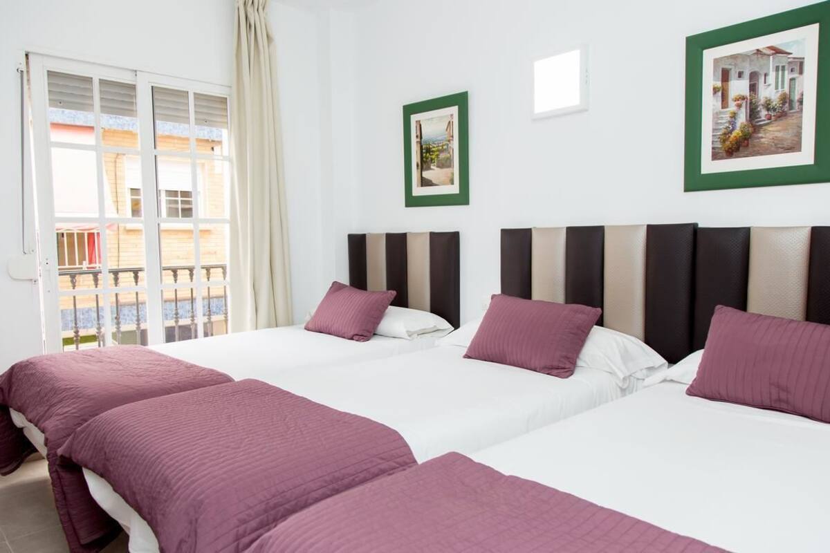 A hotel room with two beds, a balcony, and two framed pictures on the wall.