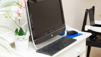 A desktop computer setup with a monitor, keyboard, and mouse on a white desk.