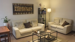 A living room with two sofas, a coffee table, a bookshelf, and a painting on the wall. - Hotel Playa Poniente (Gijon)