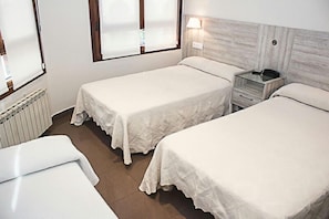 A room with two single beds, a bedside table with a lamp, and a radiator. - Hotel Playa Poniente (Gijon)