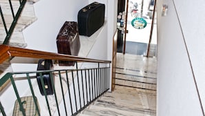 A marble staircase with a black suitcase and a green handbag on the railing. - Hotel Playa Poniente (Gijon)