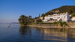 Un hôtel situé sur la côte, doté de nombreux balcons, d’une façade en pierre et offrant une vue sur la mer.