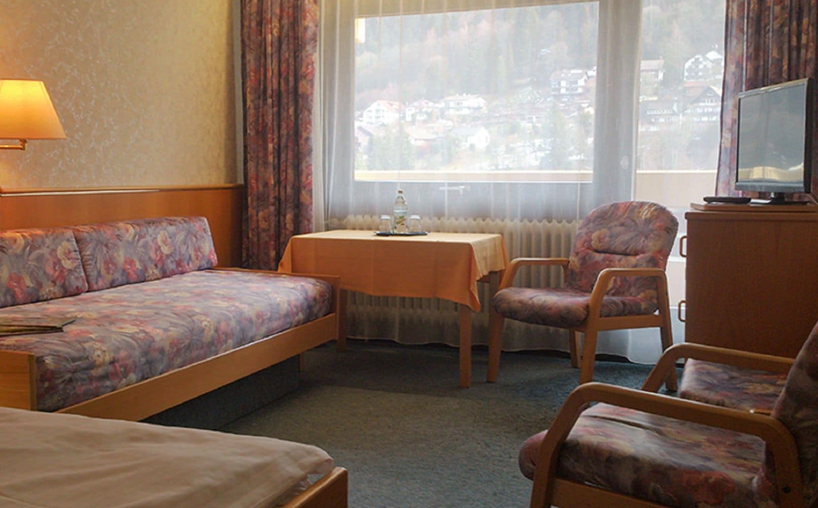 Une chambre d’hôtel avec un canapé, une petite table, une chaise et un téléviseur.