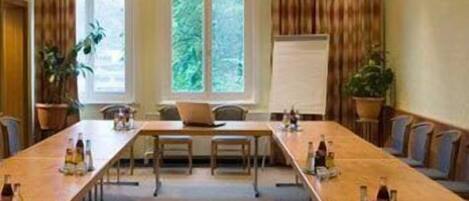 A conference room with a long table, chairs, a whiteboard, and potted plants.