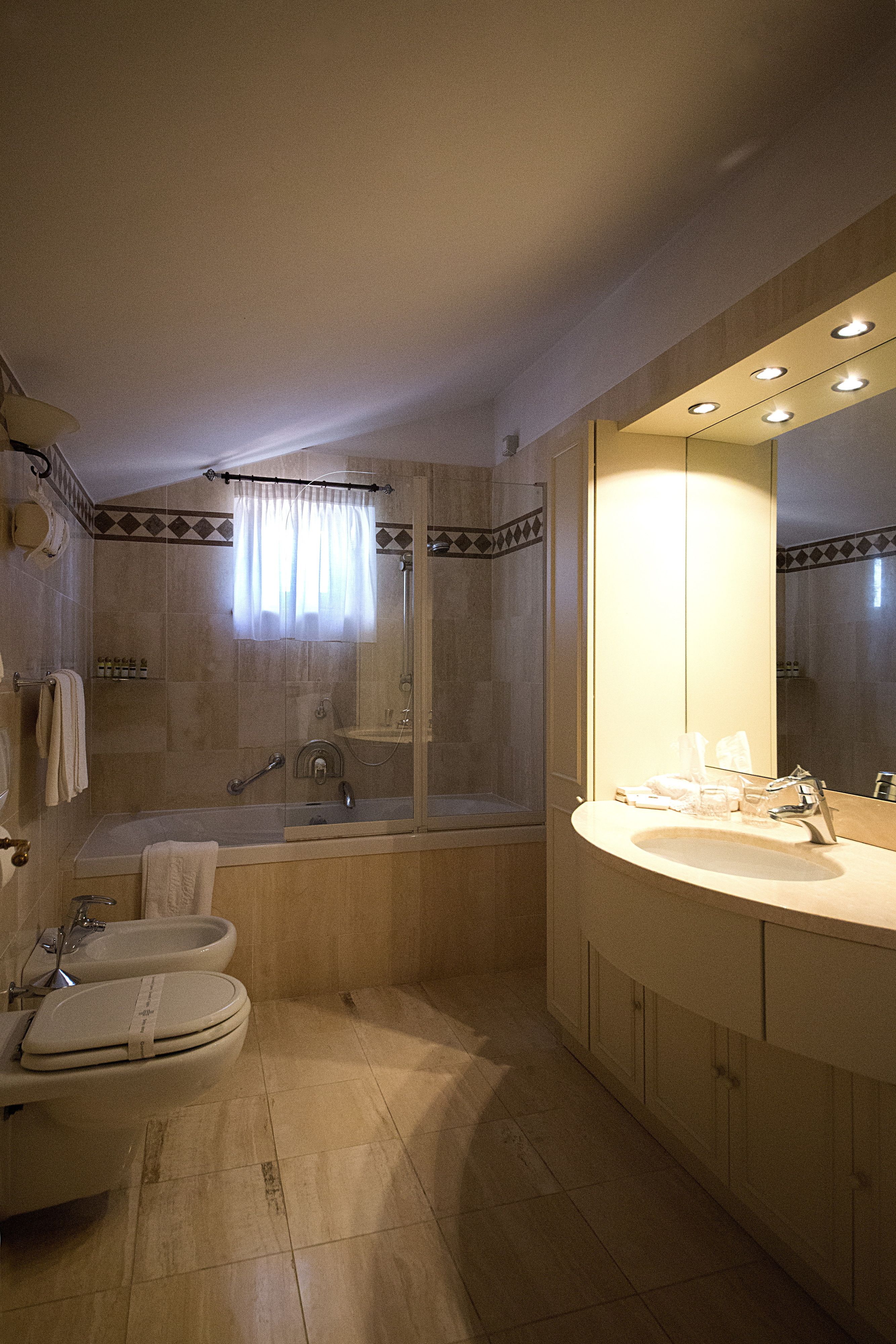 A modern bathroom with a bathtub, a large mirror, and a vanity with a sink.