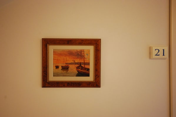 Un cuadro enmarco que muestra barcos sobre el agua, una placa con un número y una pared lisa.