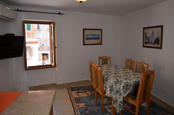 Un comedor con una mesa dispuesta para cuatro personas, un tapete estampado y dos cuadros en la pared.