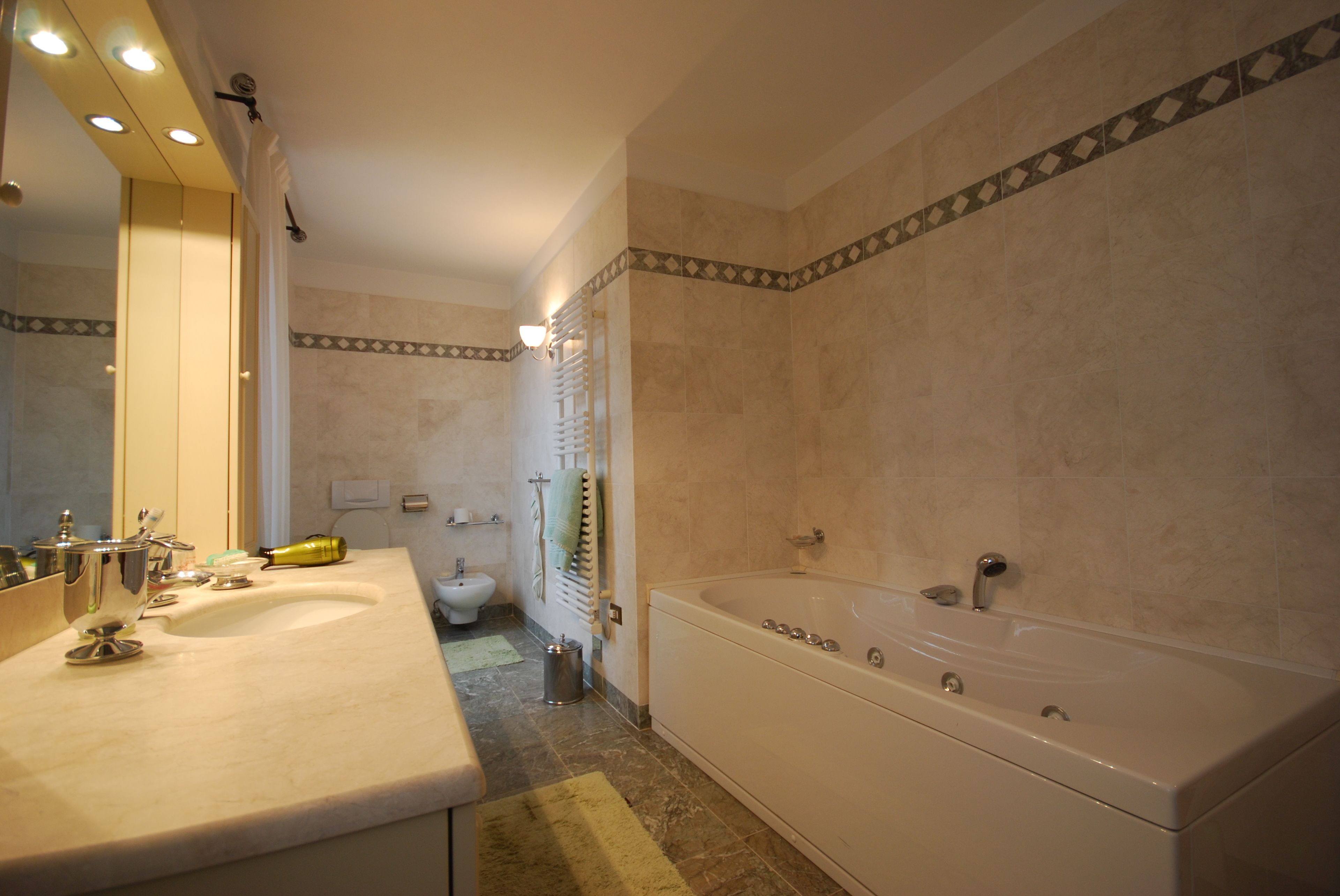 A bathroom with a double sink, a bathtub, and a large mirror.
