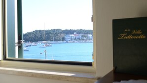 A view from a window of a coastal area with boats, a lighthouse, and buildings in the background. - Villa Tuttorotto (Rovinj)
