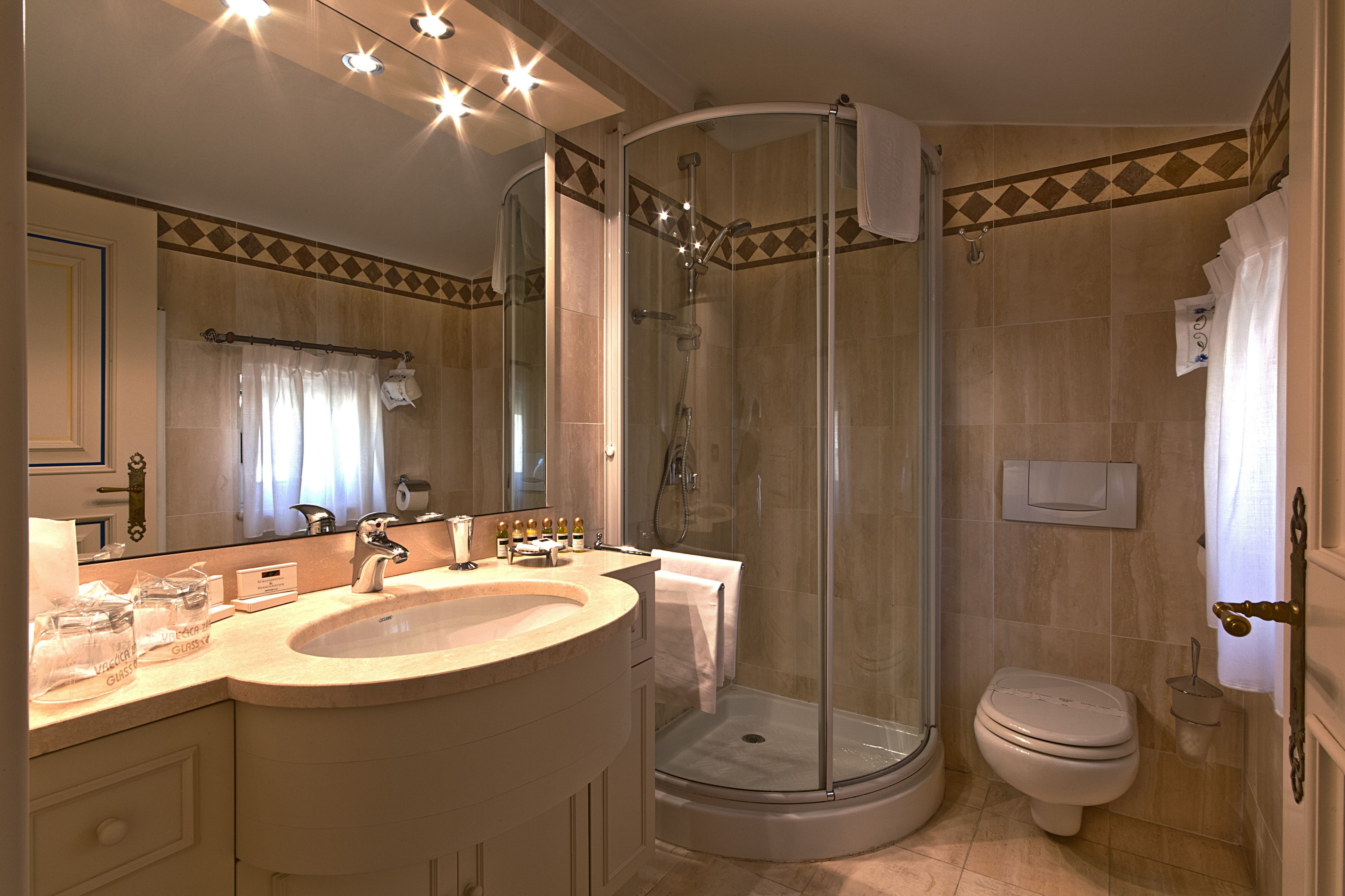 A bathroom with a curved shower enclosure, a sink with toiletries, and a toilet.