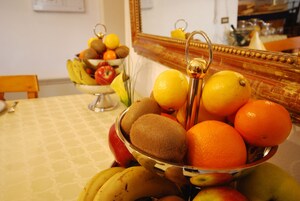 Un cuenco de frutas con plátanos, kiwis, naranjas y manzanas sobre una mesa.