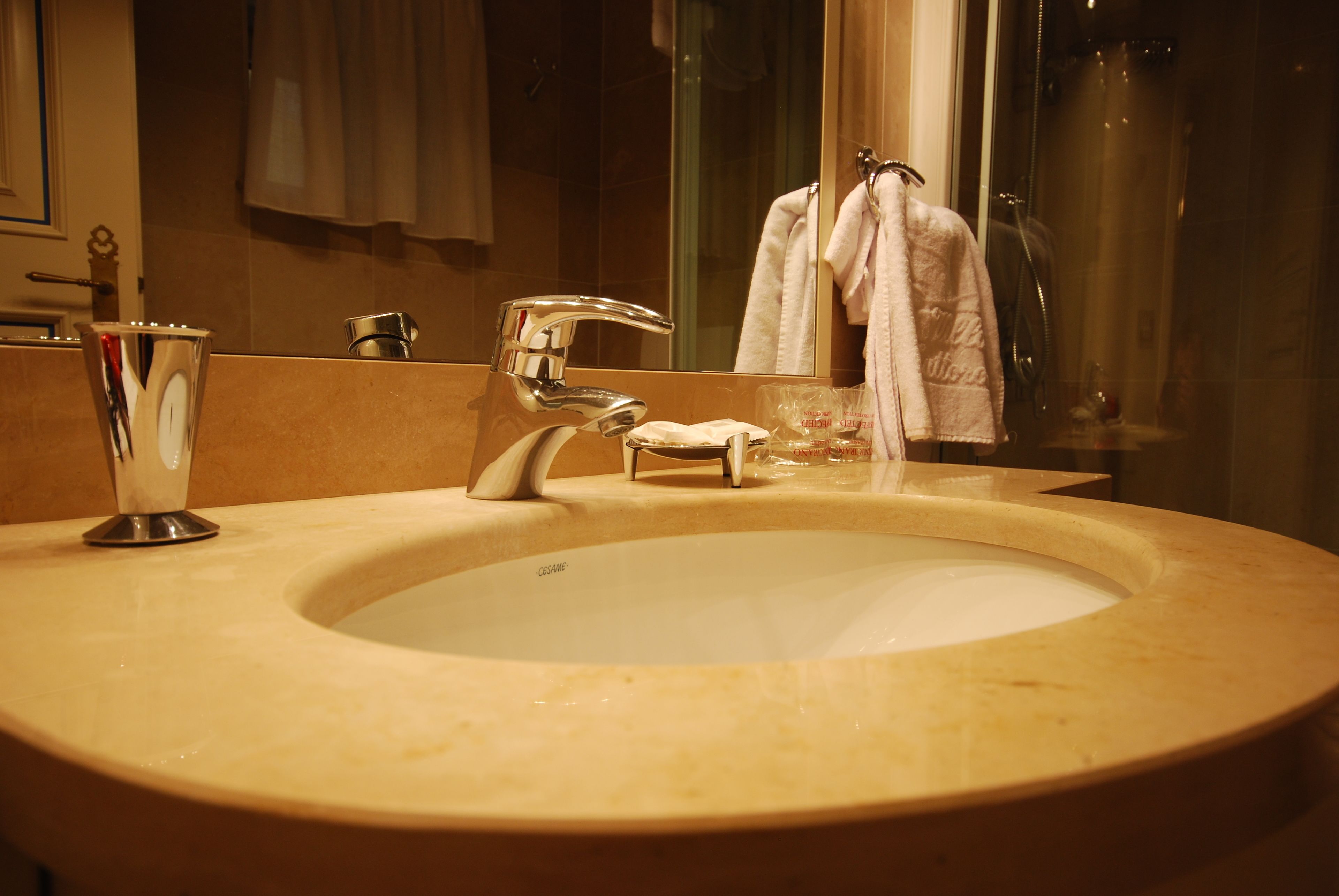 A bathroom with a large sink, a mirror, and a glass shower enclosure.