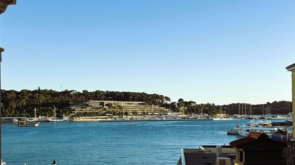A marina with boats docked, a building with multiple floors, and a hilly landscape in the background. - Villa Tuttorotto (Rovinj)