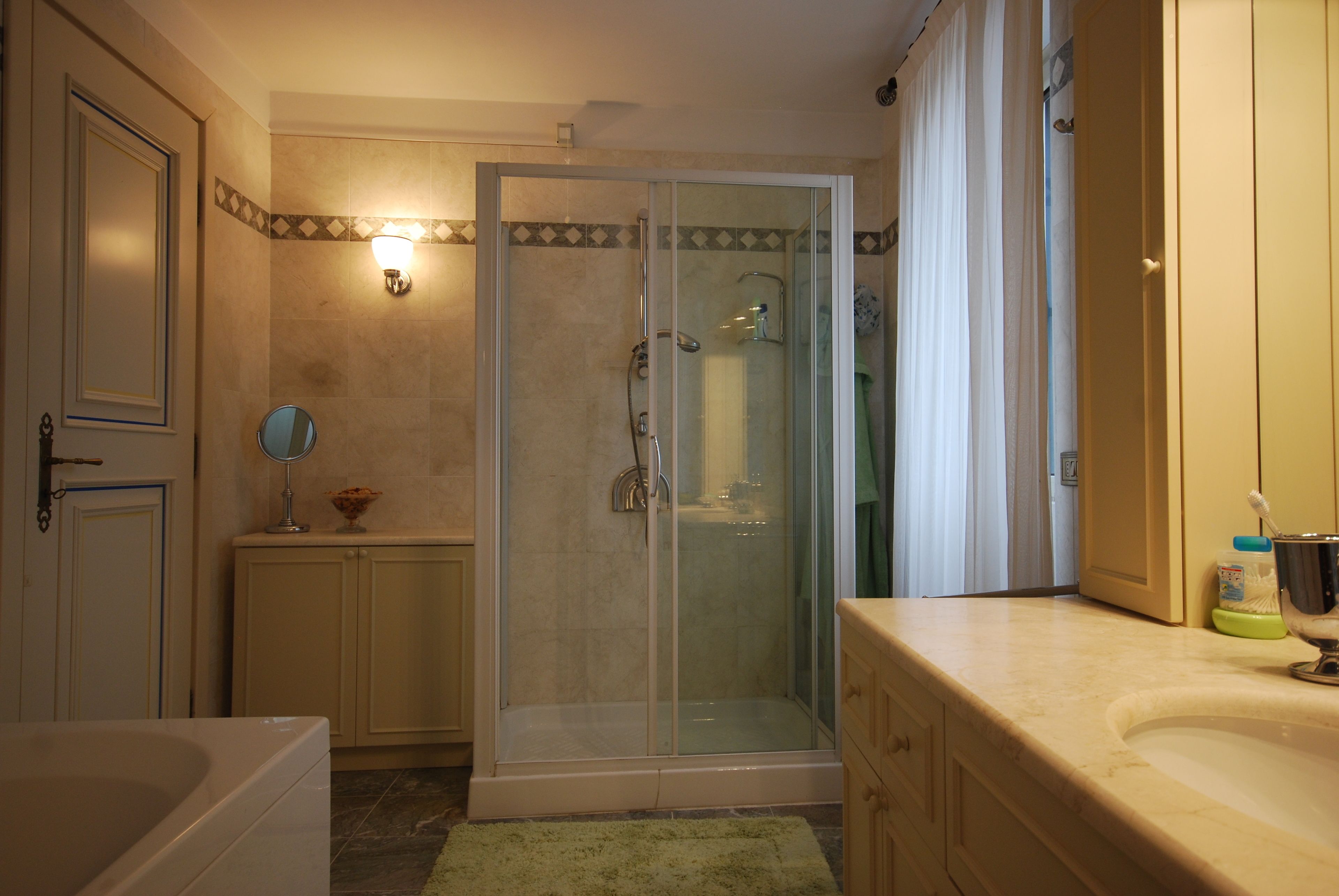 A bathroom with a glass-enclosed shower, a bathtub, a sink, and a mirror.